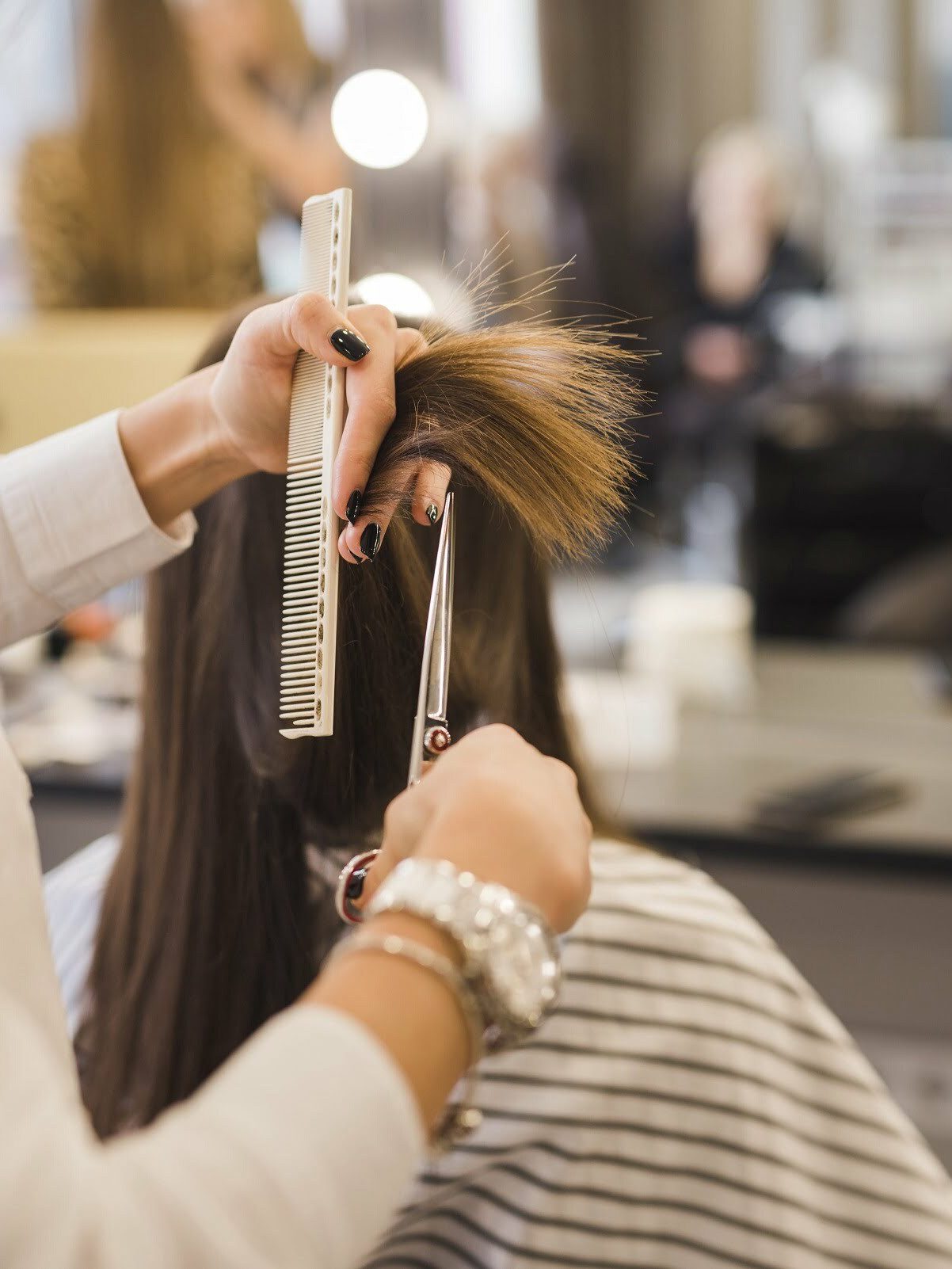 A hair stylist cutting a woman's hair at a hair salon