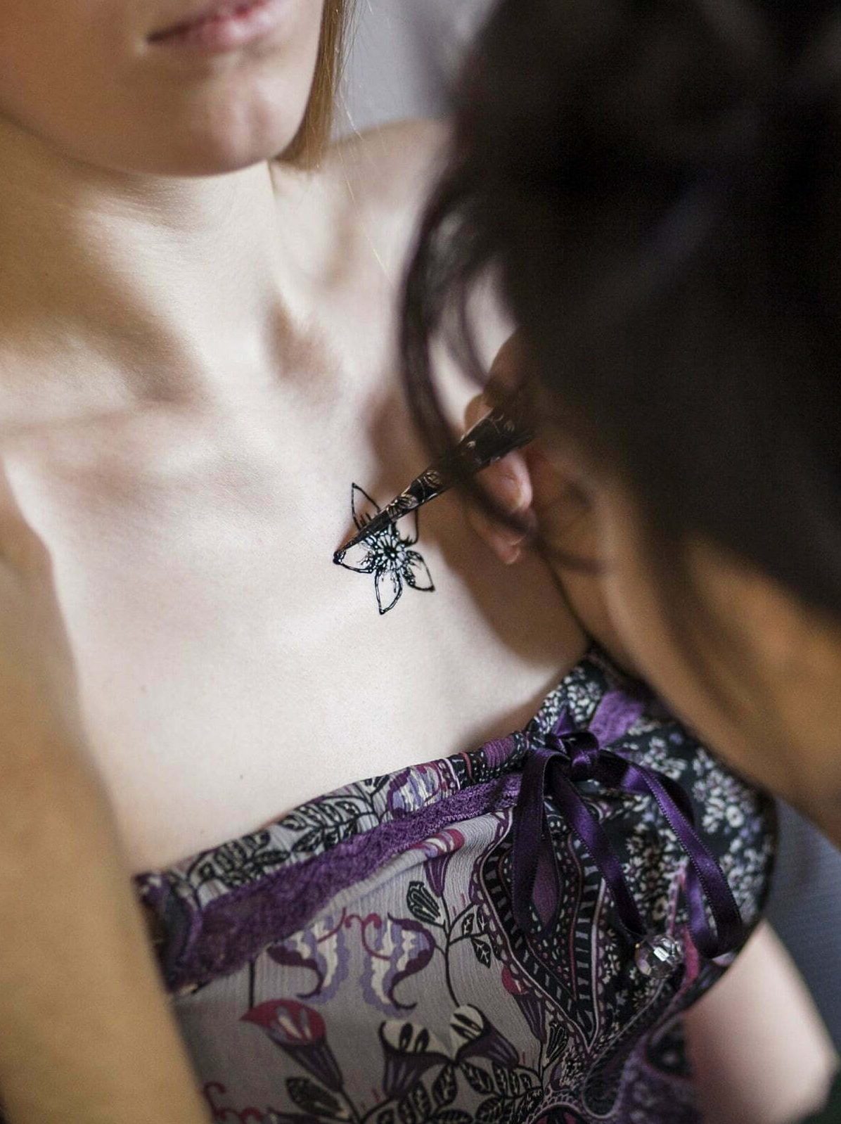 Woman having henna tattoo done on her chest